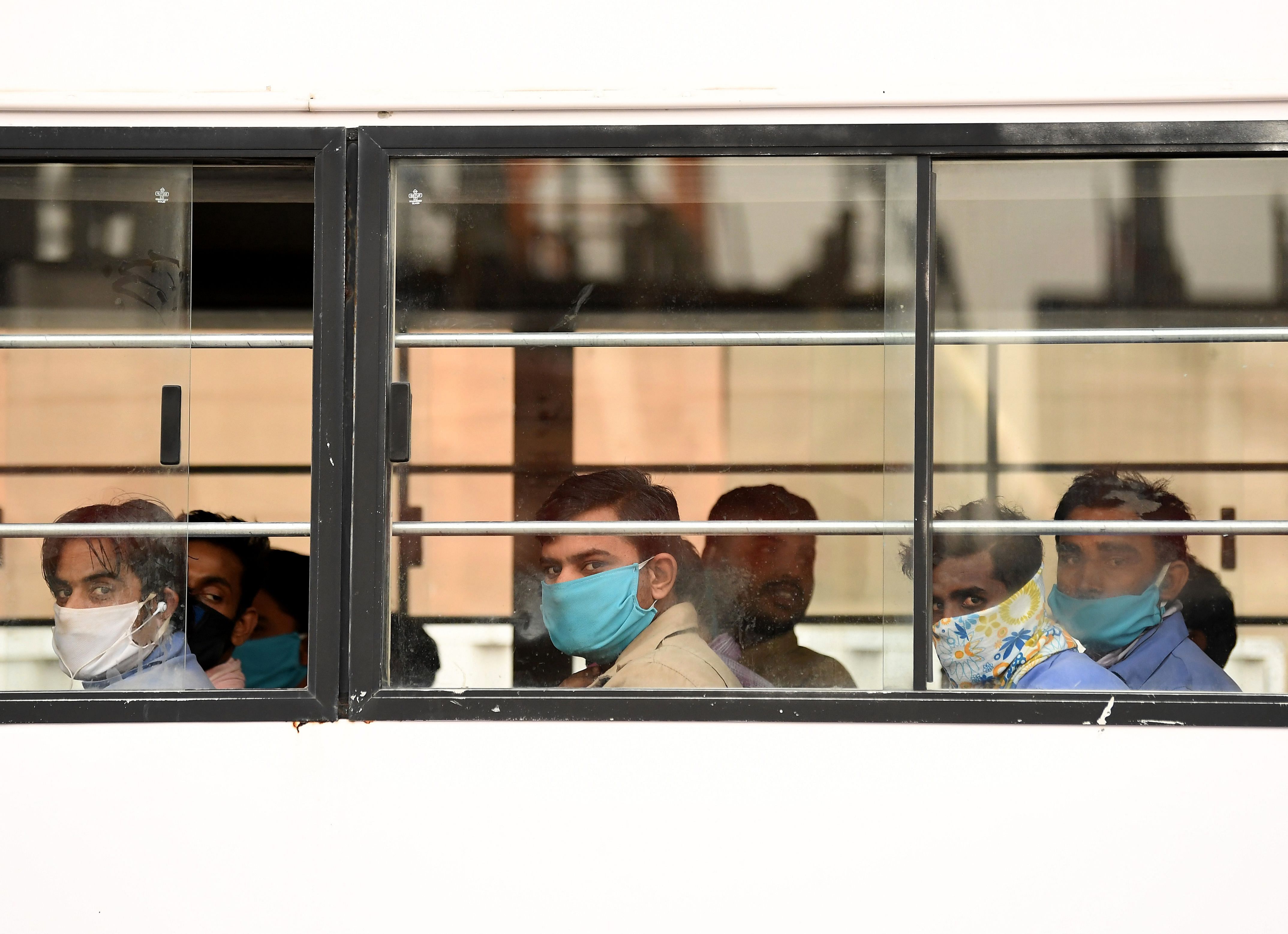 Foreign workers wearing masks to protect their faces, ride a bus transporting them to their workplace in Dubai. (Credit: AFP Photo)