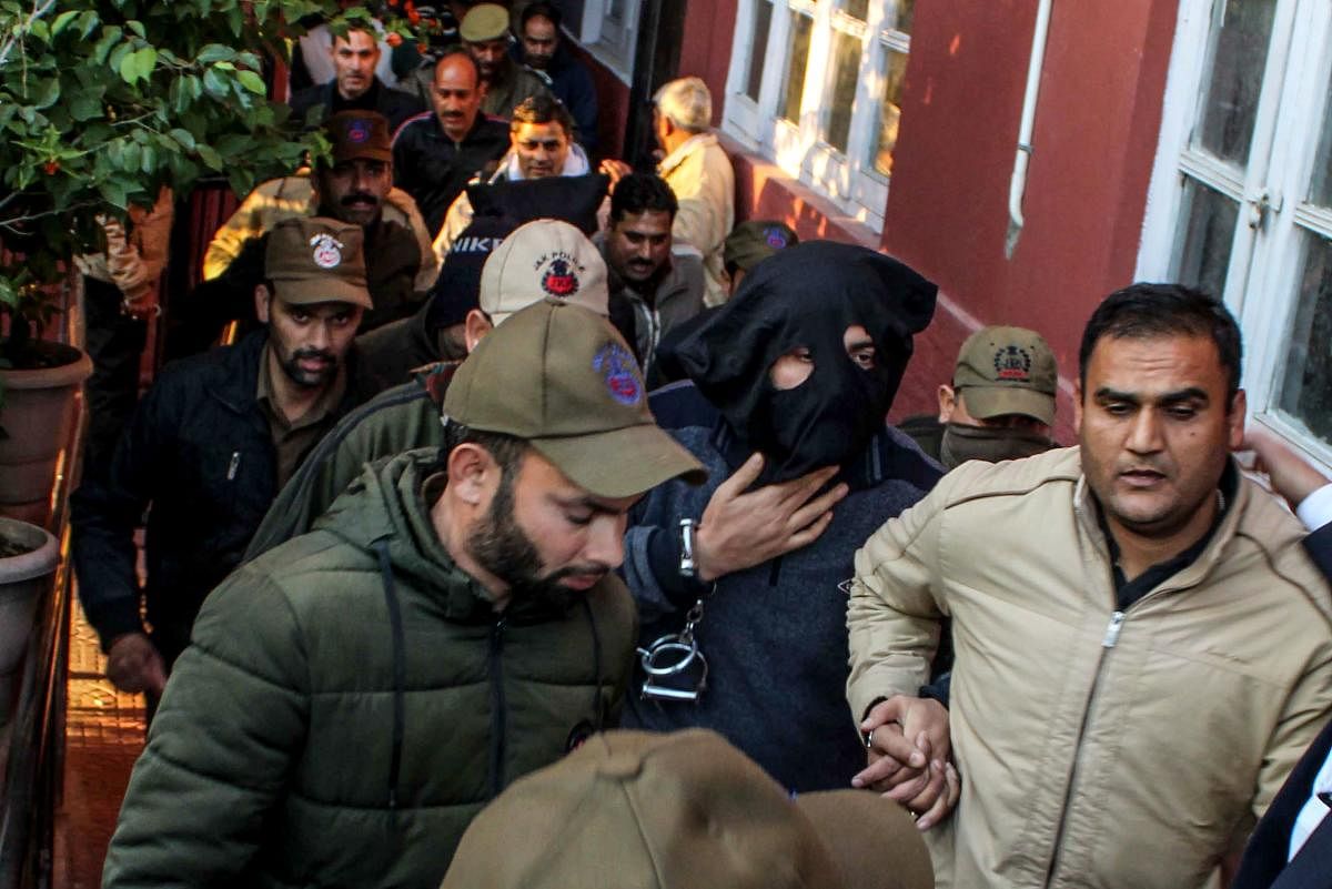 Suspended Deputy Superintendent of Jammu and Kashmir Police Davinder Singh (2R hooded), who was arrested for helping two terrorists travelling out of Jammu and Kashmir, is escorted after being produced at a special court in Jammu on January 23, 2020. Credit: AFP Photo