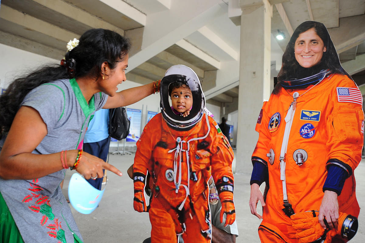 A woman helps her child wear spacesuit at a gallery at Satish Dhawan Space Centre, Sriharikota. Isro is bracing for India's first manned spaceflight. The Rs 10k-crore mission will see three-member crew blast off aboard Gaganyaan in Dec 2021. (DH File Photo)