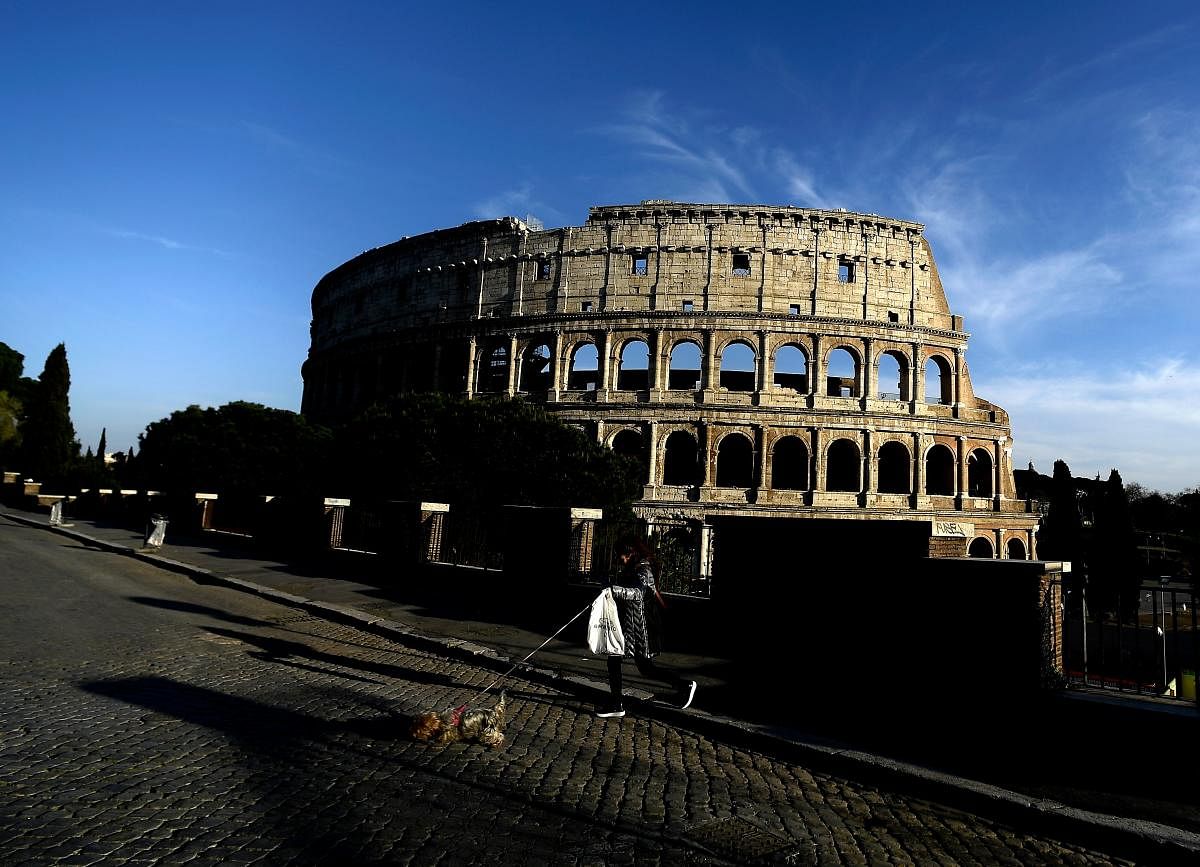 A woman walks with her dog by the Colosseum on April 2, 2020 in Rome, during the country's lockdown aimed at curbing the spread of the COVID-19 infection, caused by the novel coronavirus. Credit: AFP Photo