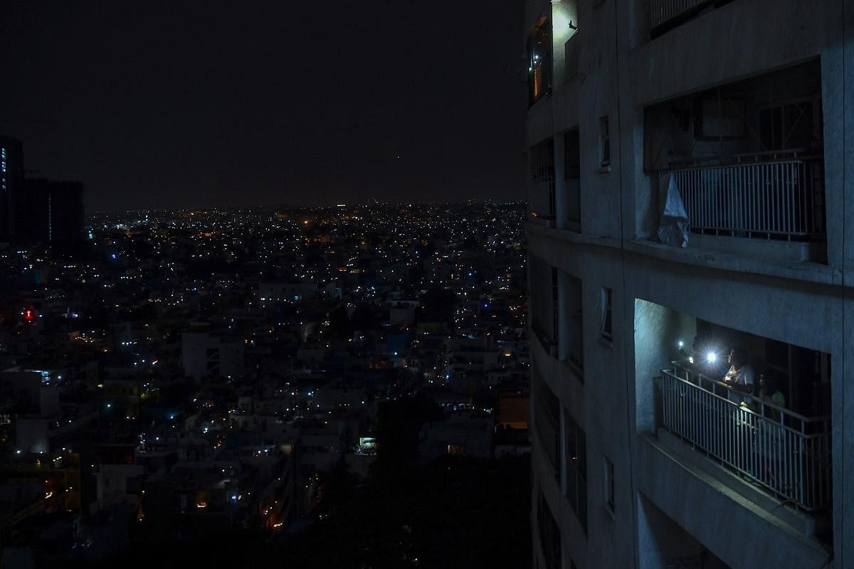 Residents light candles and turn on their mobile phone lights in their balcony to observe a nine-minute vigil called by PM Modi. AFP