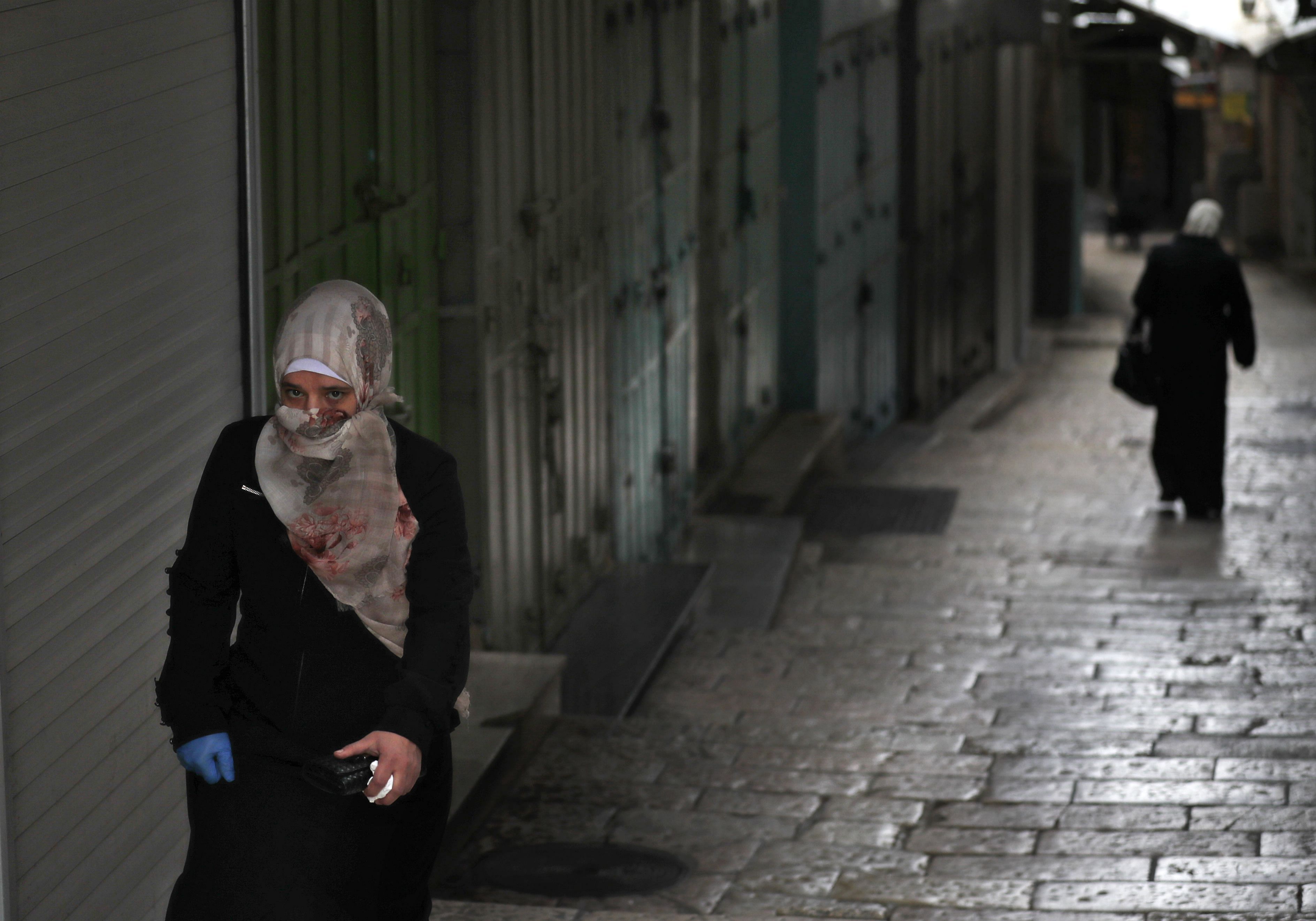 A woman walks in an alley past closed shops due to the COVID-19 coronavirus pandemic in Jerusalem's Old City/ Representative photo. (Credit: AFP)