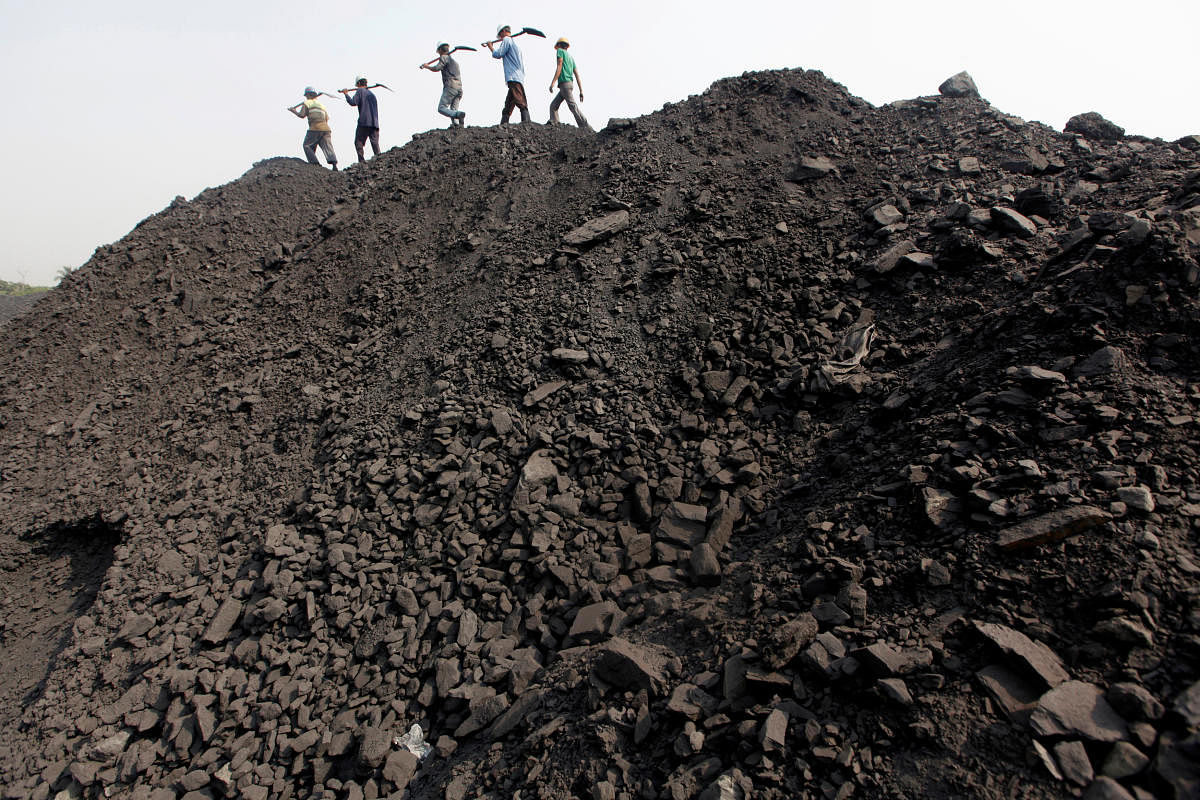 Workers walk on a heap of coal at a stockyard of an underground coal mine in the Mahanadi coal fields at Dera, near Talcher town. Credit: Reuters Photo