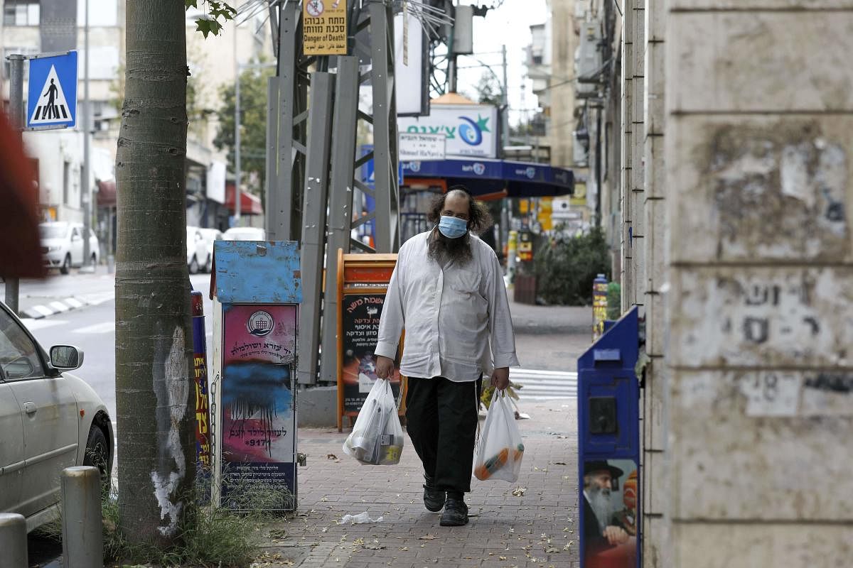 An ultra-Orthodox Jewish man wearing a protective mask, walks by carrying bags of shopping in the religious Israeli city of Bnei Brak, near Tel Aviv, on April 06, 2020 during the novel coronavirus pandemic crisis. Credit: AFP Photo