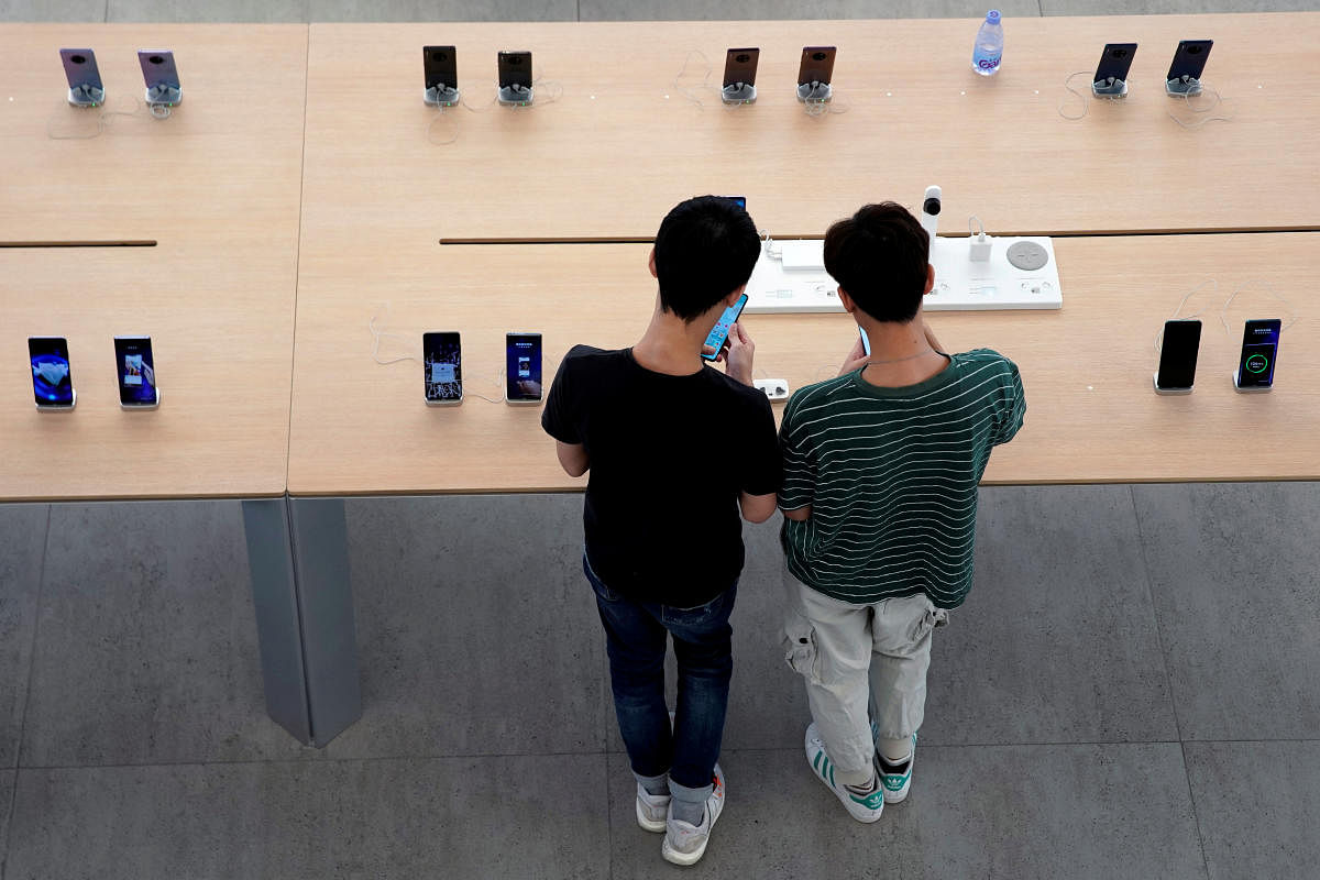 File Photo: People look at smartphones in Huawei's first global flagship store in Shenzhen, Guangdong province, China October 30, 2019. (Credit: REUTERS/Aly Song)