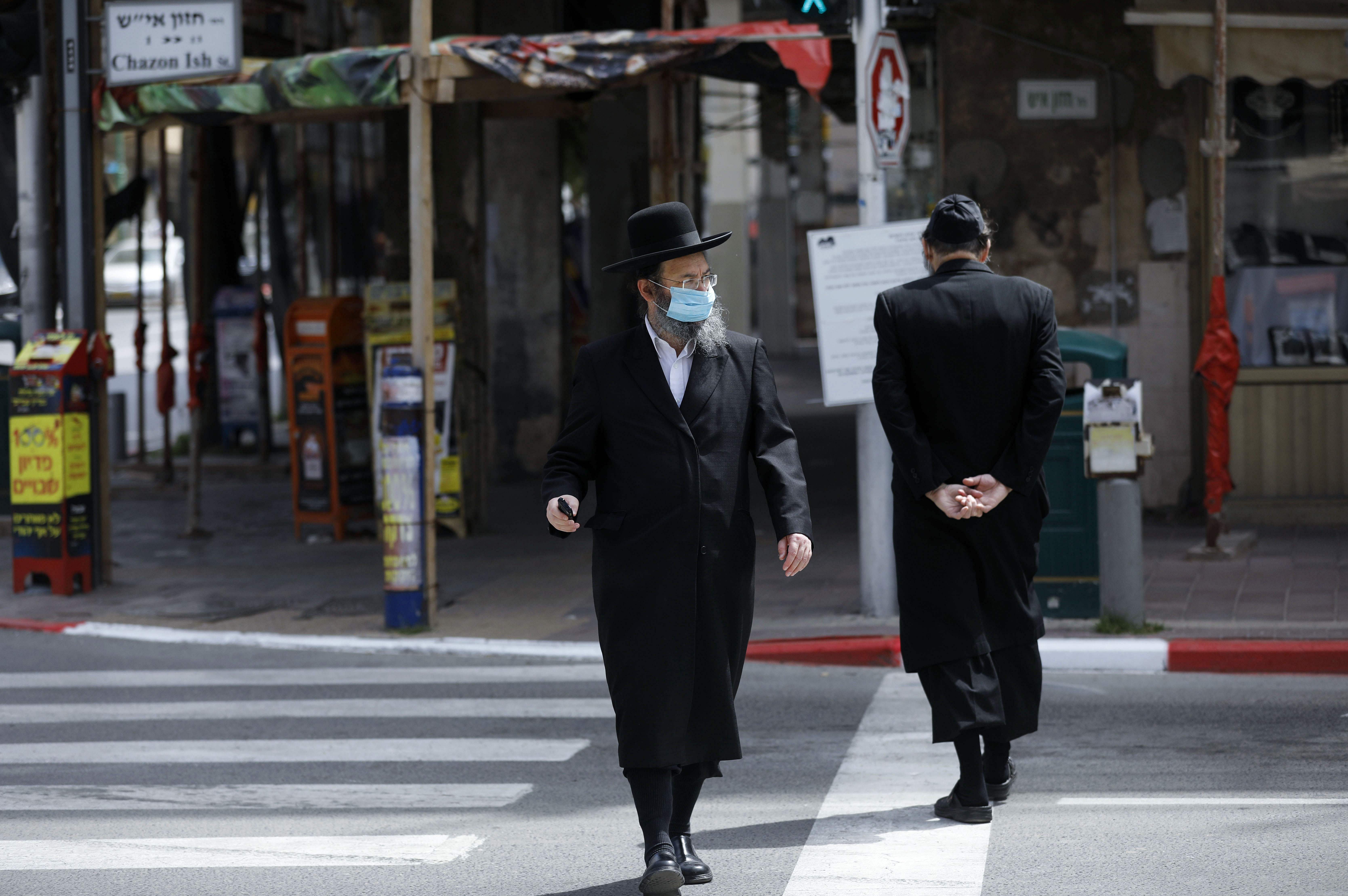 An ultra-Orthodox Jewish man wearing a protective mask crosses a street in the religious Israeli city of Bnei Brak, near Tel Aviv. (Credit: AFP)