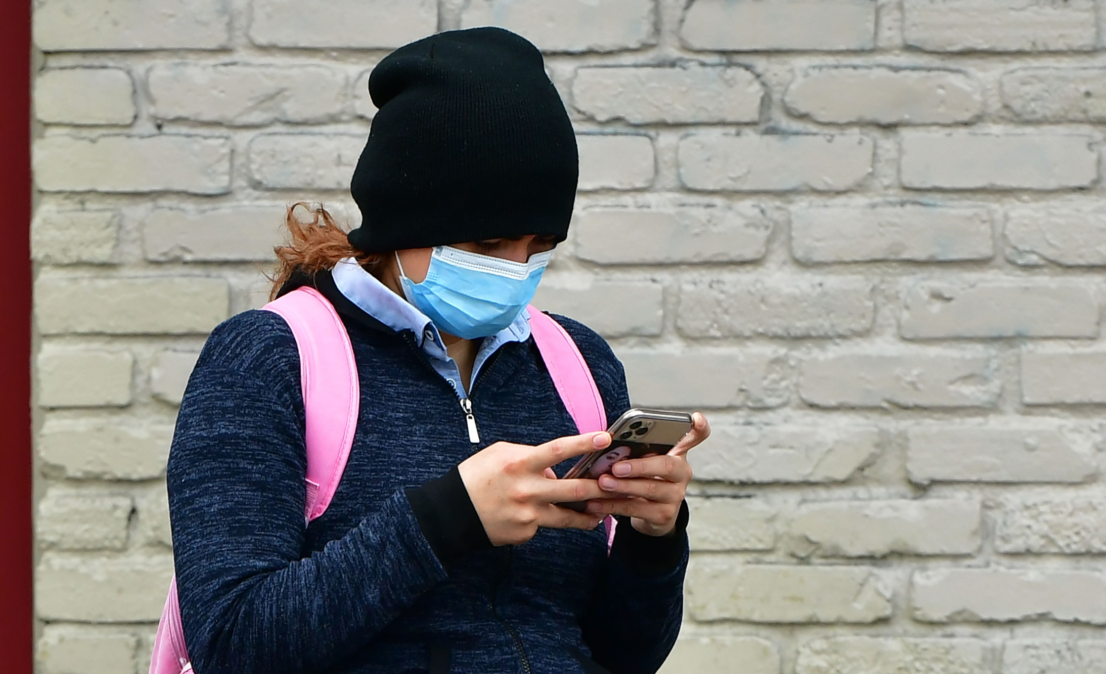 A woman wears a face mask while checking her cellphone in Los Angeles. (Credit: AFP Photo)