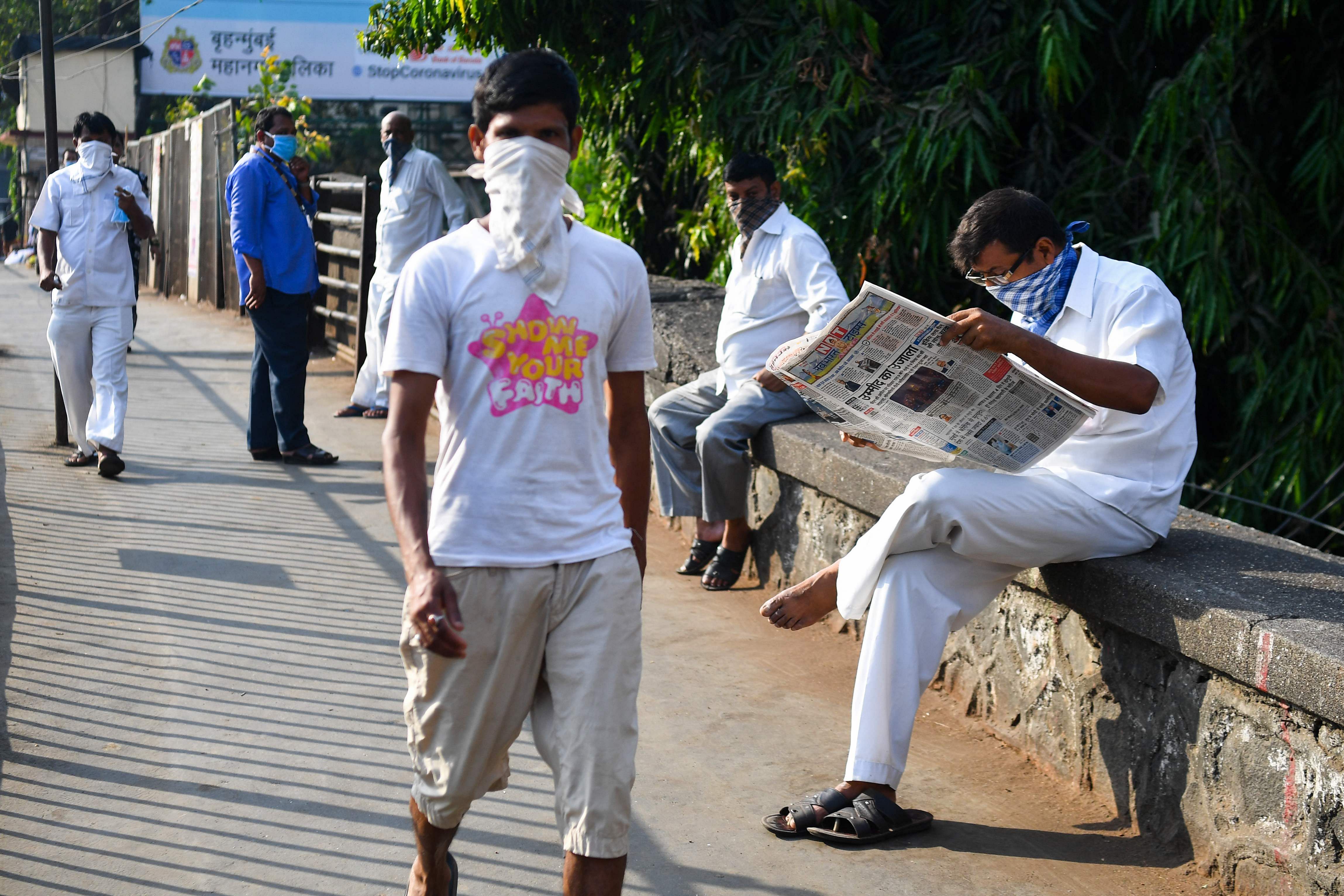 A man reads a newspaper on a bridge leading to the Dharavi slum during a government-imposed nationwide lockdown as a preventive measure against the spread of the COVID-19 coronavirus, in Mumbai. (Credit: AFP Photo)