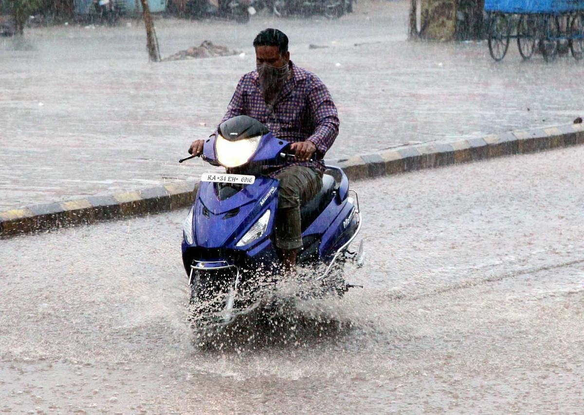 A motorist wades through rainwater in Ballari on Tuesday. DH photo