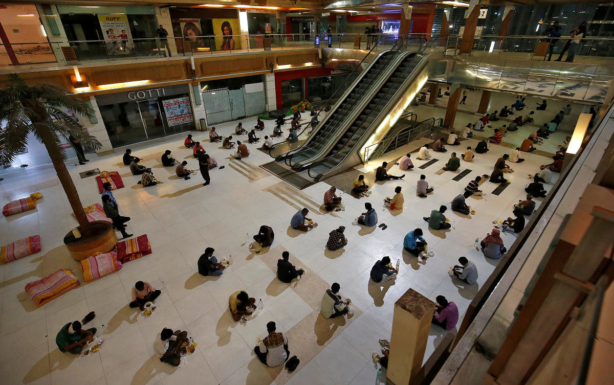 Migrant workers eat their dinner inside a shopping mall turned into a shelter during a 21-day nationwide lockdown in Ahmedabad, April 7, 2020. REUTERS