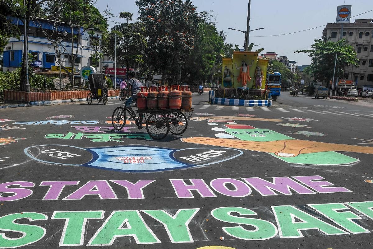 A man rides a three-wheeler cart loaded with gas cylinders (C) as he crosses a road covered with paintings about precautions to follow during a government-imposed nationwide lockdown as a preventive measure against the COVID-19 coronavirus, in Kolkata on April 7, 2020. Credit: AFP Photo