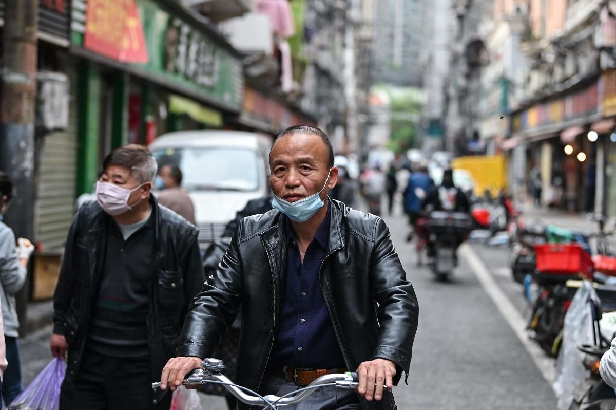A man wearing a face mask rides a bicycle on a street in Wuhan in China's central Hubei province  (AFP Photo)