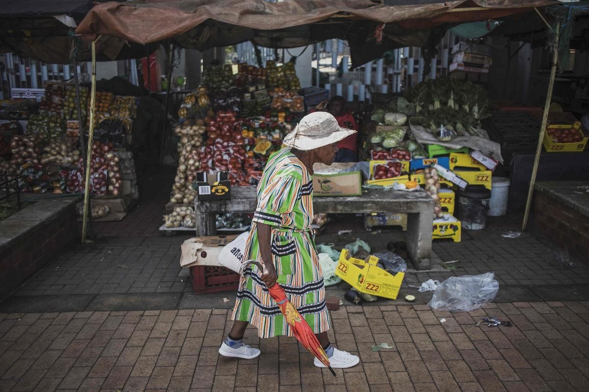 A woman walks by a food stall at an open air market in Kliptown, Soweto. AFP