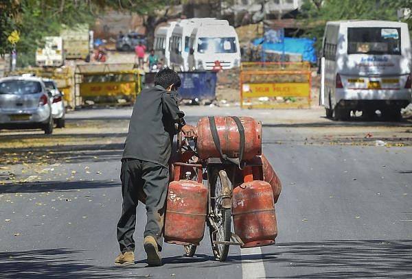 A worker carries LPG gas cylinders on a deserted road during the nationwide lockdown in wake of coronavirus pandemic, in New Delhi. (PTI Photo/Kamal Singh)