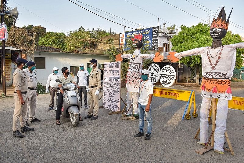 Effigies raised in the middle of a road, to create awareness about maintaining social distance, as policemen stop commuters during the nationwide lockdown imposed to curb the coronavirus pandemic. (PTI Photo)