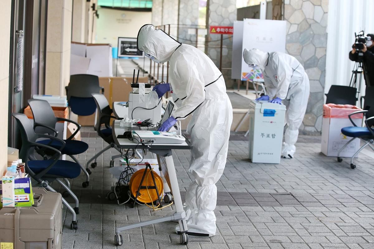 Election officials wearing protective clothing set up a polling station for absentee voting of the COVID-19 coronavirus patients at a quarantine facility in Gyeongju. AFP