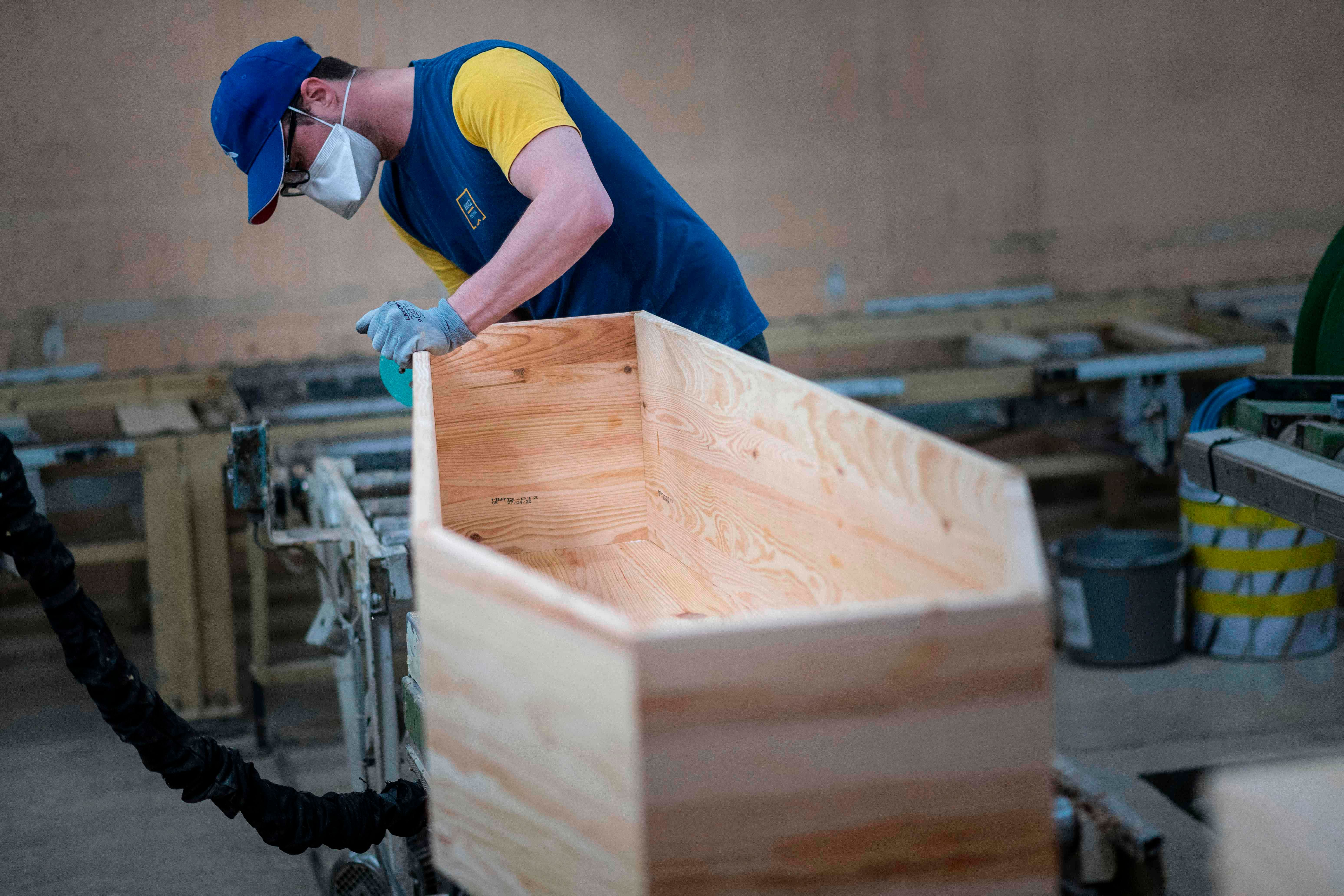 An employee of France's biggest coffin-maker, OGF group polishes a coffin in Jussey, eastern France, on April 8, 2020, amid the spread of the COVID-19. (Credit: AFP Photo)