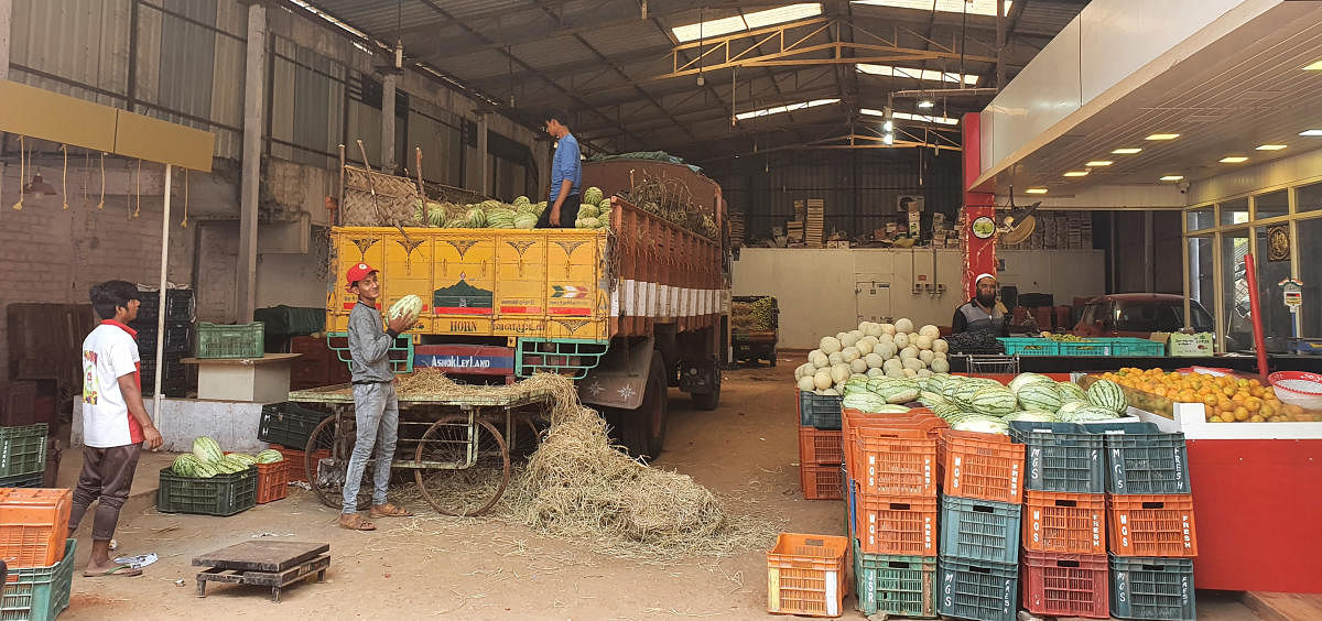 Workers unload fruits from a lorry at a fruit mandi in Chikkamagaluru.