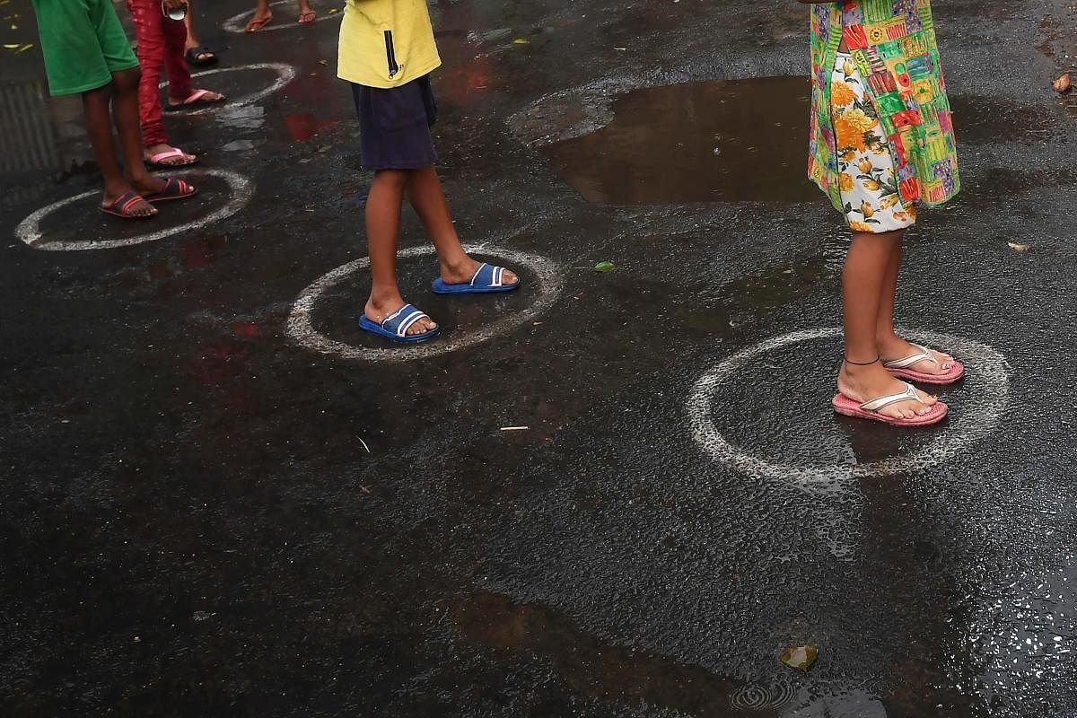 Children stand in queue to collect food as it rains during the lockdown in Kolkata on April 12, 2020. PTI