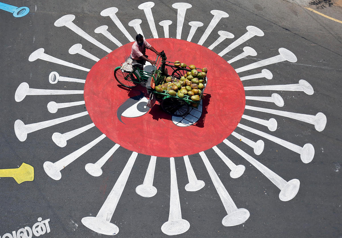 A man selling coconuts rides his trishaw on a graffiti on a road depicting the coronavirus as an attempt to raise awareness about the importance of staying at home during a 21-day nationwide lockdown to slow the spreading of the coronavirus disease (COVID-19), in Chennai, India, April 13, 2020. Credit: Reuters Photo