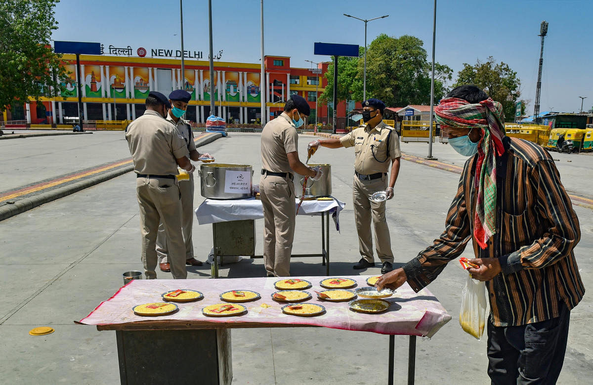 RPF personnel distribute food among needy people at New Delhi Railway Station during the nationwide lockdown to curb the spread of coronavirus. PTI