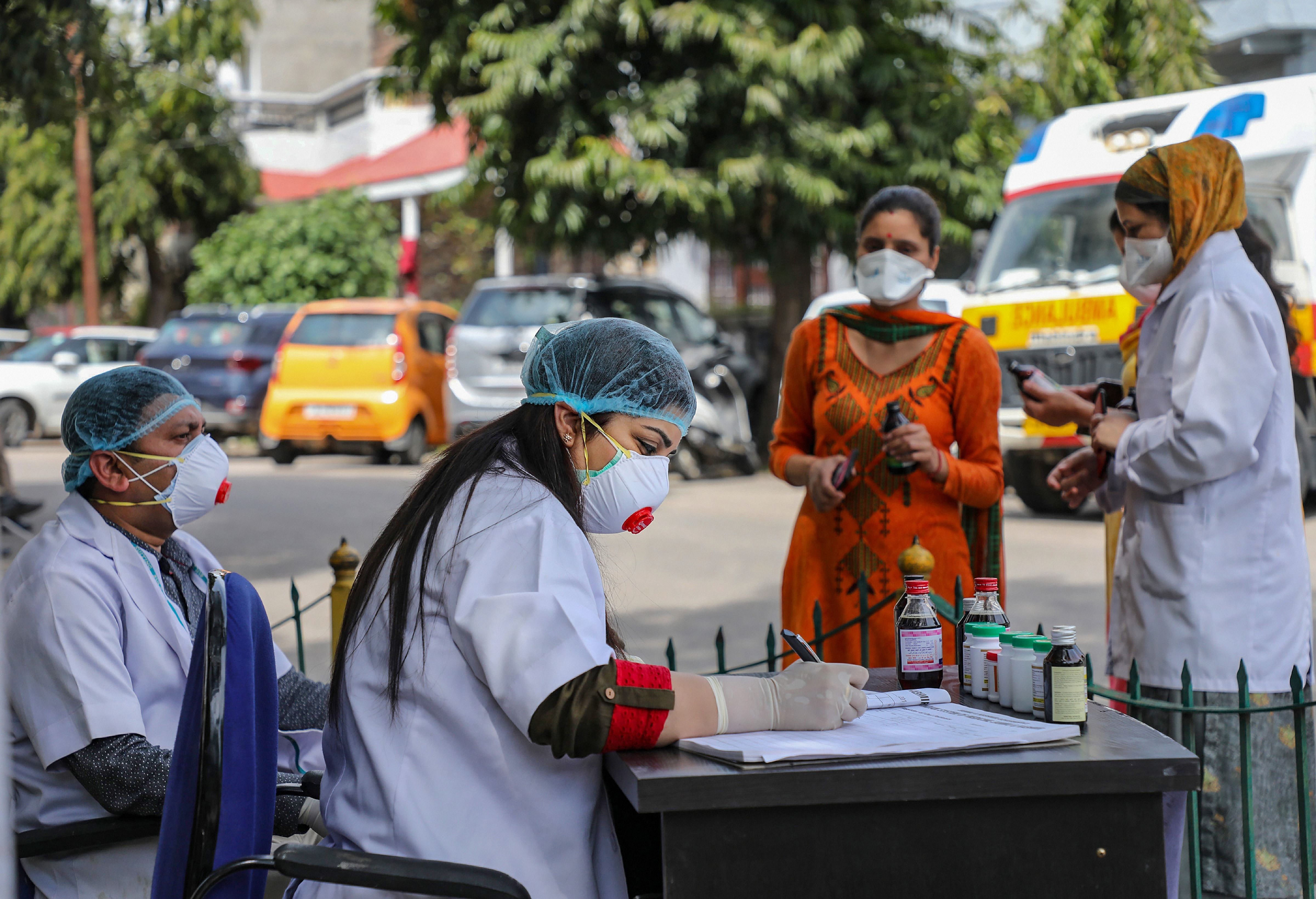 Doctors wearing protective suits as a precautionary measure against the coronavirus check patients outside an isolation ward at Govt. Medical College hospital in Jammu. (Credit: PTI Photo)