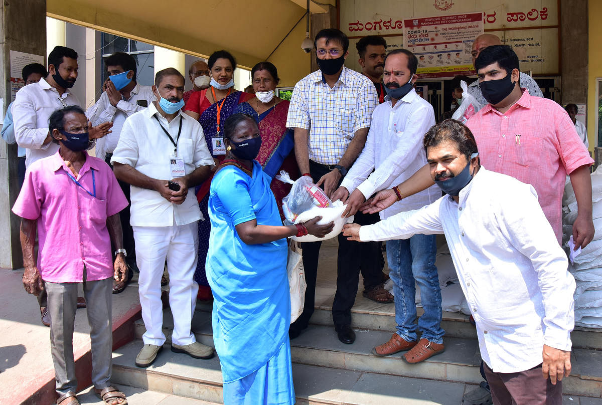 Mayor Diwakar, MLA Vedavyas Kamath and MCC Commissioner Ajith Kumar Hegde Shanady distribute food kits to needy at the MCC building at Lalbagh in Mangaluru. DH photo/ Govindraj Javali