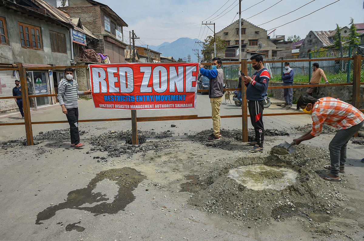 Workers place a banner after erecting a road blockade at an identified red zone area for COVID-19 during a nationwide lockdown  (PTI Photo)