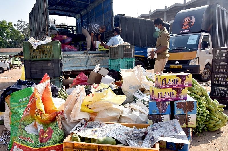 Workers loading vegetables, fruits to vans for sale at apartments around the Bengaluru. (DH Photo)