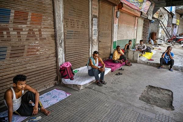 Migrant workers take rest outside the closed shop during the nationwide lockdown imposed as a preventive measure against the coronavirus outbreak, in Allahabad, Tuesday, April 14, 2020. (PTI Photo)