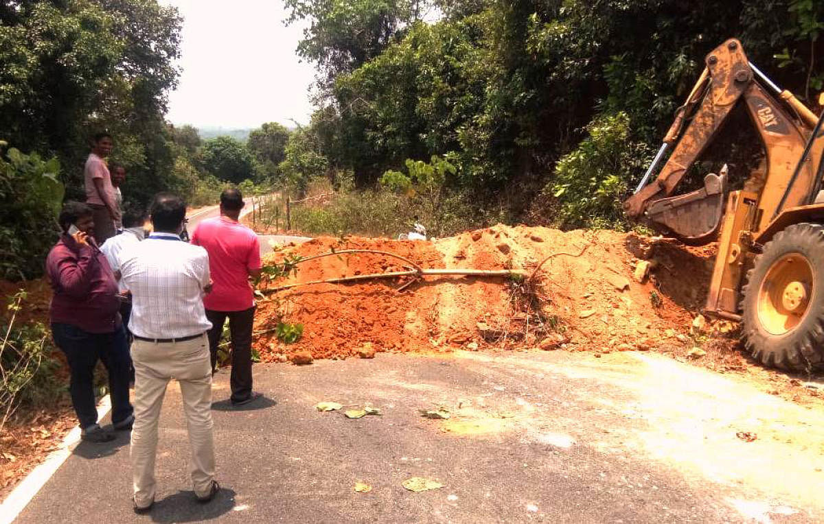 Officials close the road connecting Kantavara in Karkala to Beluvai in Dakshina Kannada by dumping mud with the help of an excavator. DH Photo.