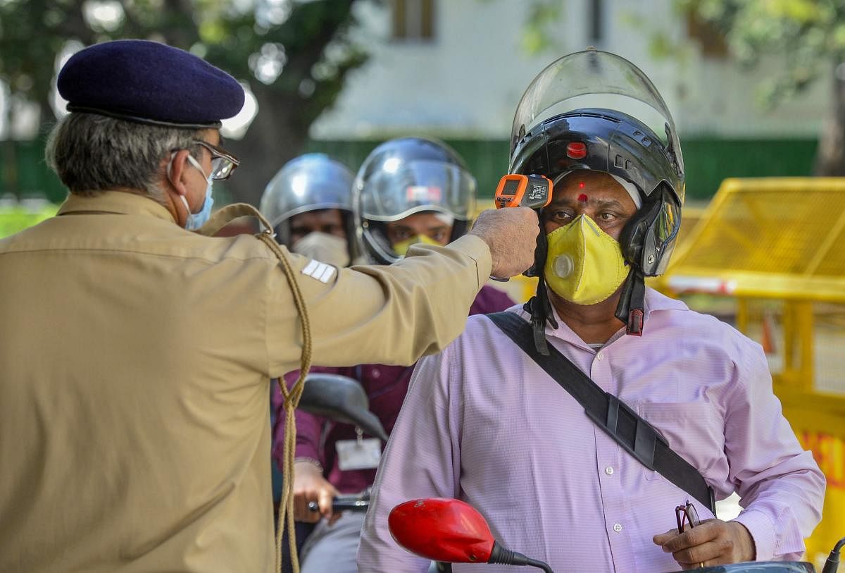  A security officer uses a thermal screening device on an employee at the entrance of the Health Ministry offiice (PTI Photo)