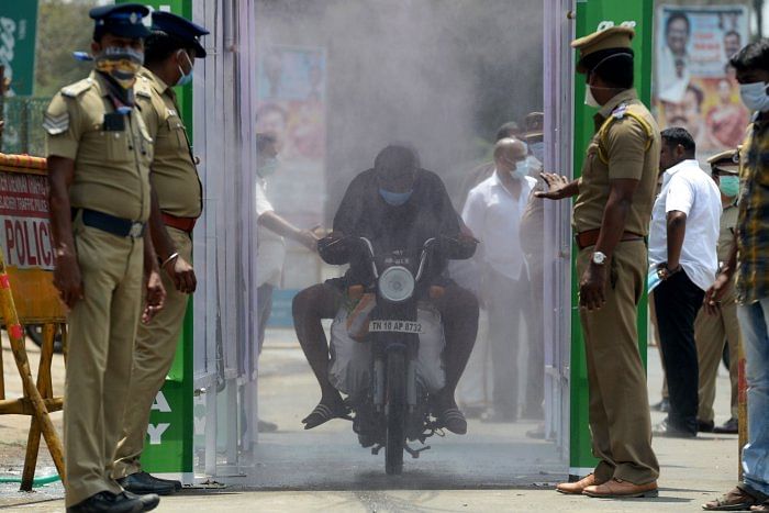 A motorist rides through a disinfection tunnel in Chennai. (Credit: AFP) 