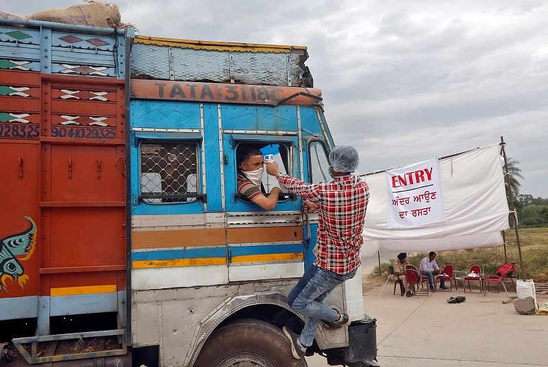  health worker uses an infrared thermometer to check the temperature of a truck driver. (Reuters Photo)