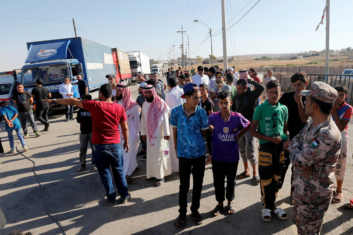 People gather while trucks loaded with humanitarian supplies to be delivered for displaced Syrians, wait at the Jordanian city of Mafraq, near the border with Syria. (Reuters Photo)