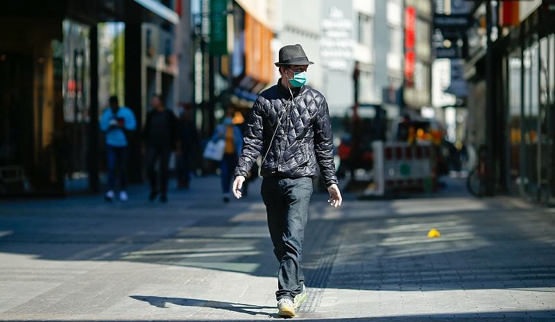 A man, wearing a protective mask and gloves, walks at the shopping district "Hohe Strasse", as the spread of the coronavirus disease (COVID-19). (Reuters Photo)