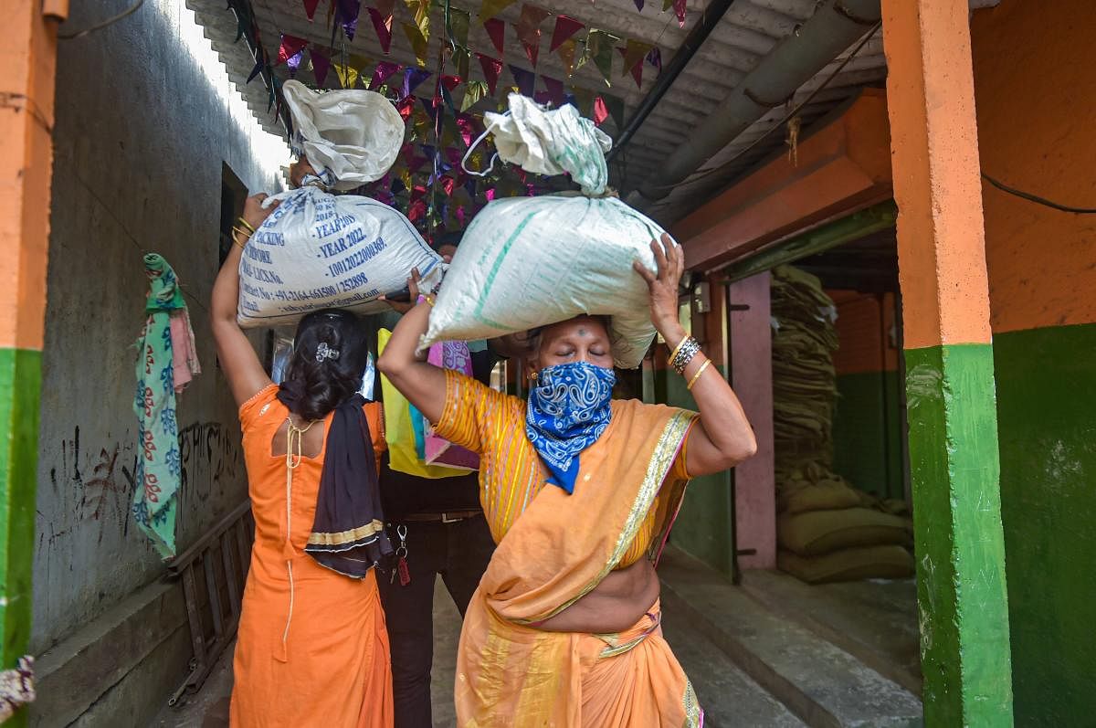 People carry essential food items after collecting them from a ration store (PTI Photo)