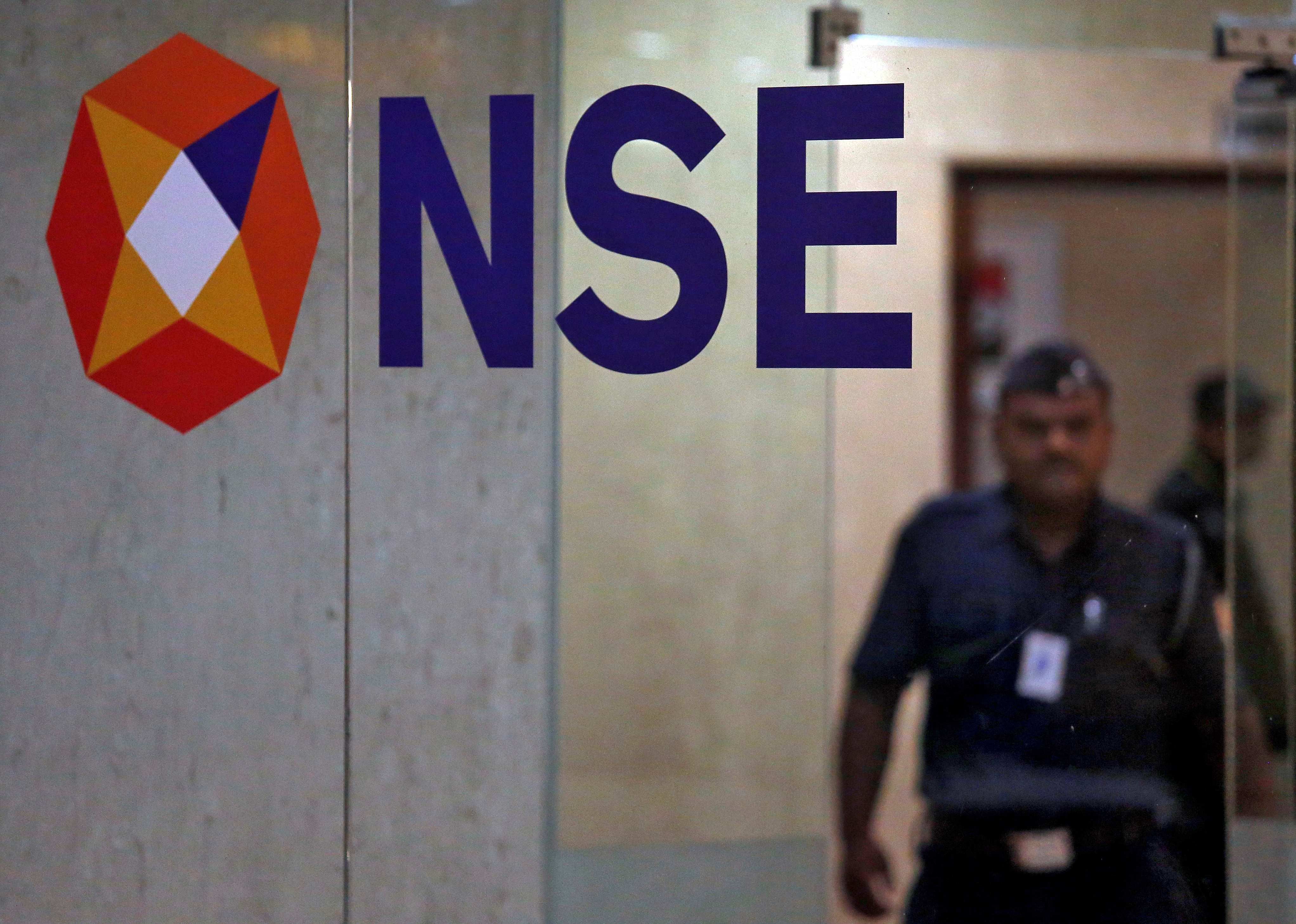 A security guard walks past the logo of the National Stock Exchange (NSE) inside its building in Mumbai. (Credit: Reuters)