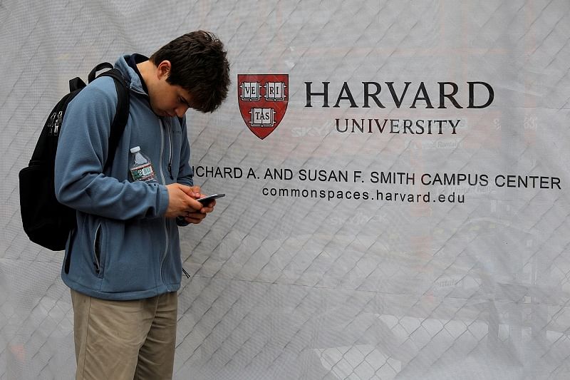A man looks at his mobile phone beside a sign for Harvard University in Cambridge. (Reuters Photo)