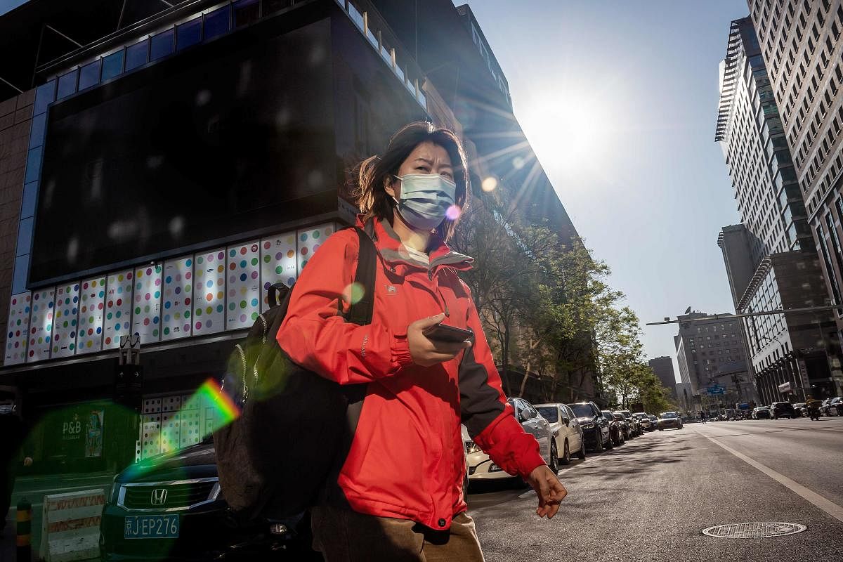 A woman wearing a face mask amid concerns over the COVID-19 coronavirus crosses a street in Beijing on April 22, 2020. Credit: AFP Photo