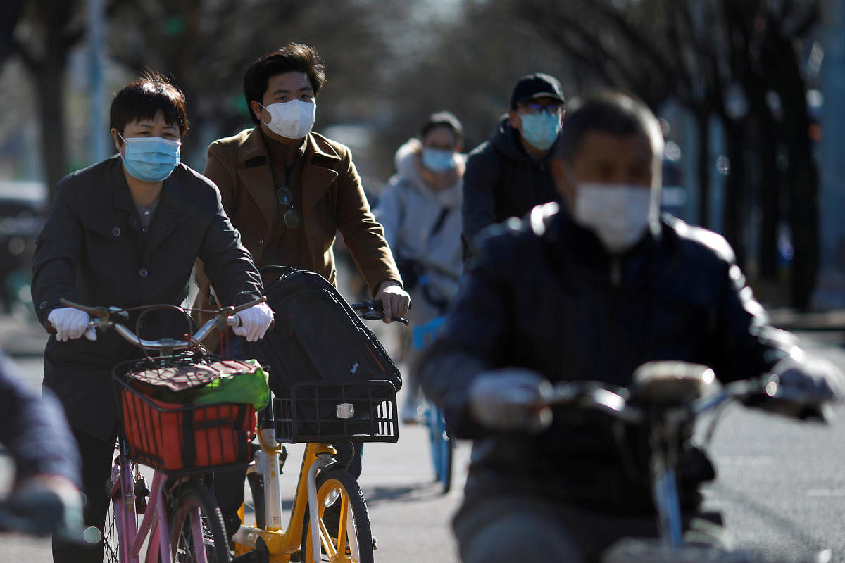 People wearing face masks ride bikes following an outbreak of the coronavirus disease (COVID-19), in Beijing, China March 27, 2020. Credit: Reuters File Photo