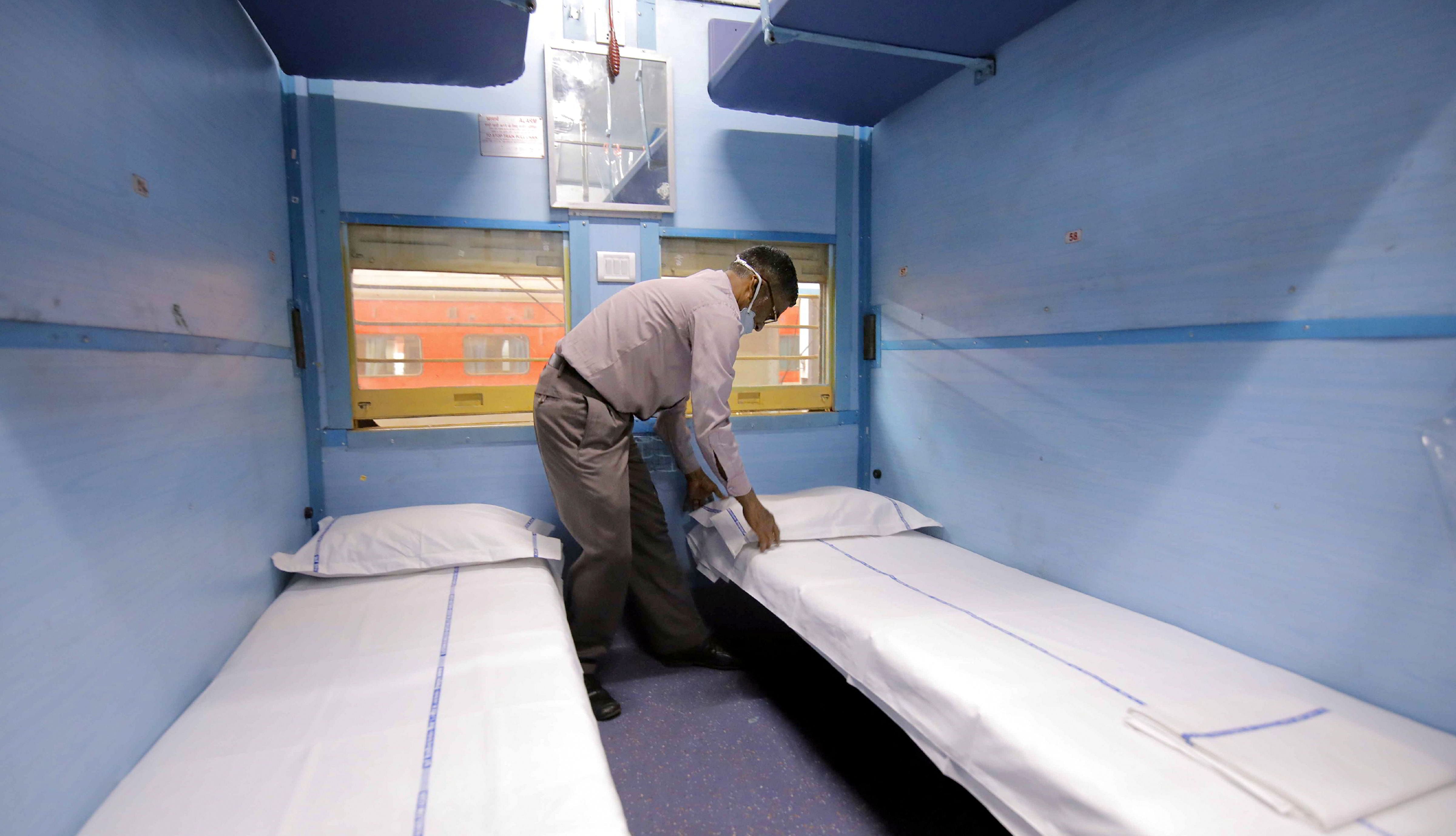 Railways worker prepares a train coach converted into isolation ward for COVID 19 patients. (Credit: PTI Photo)