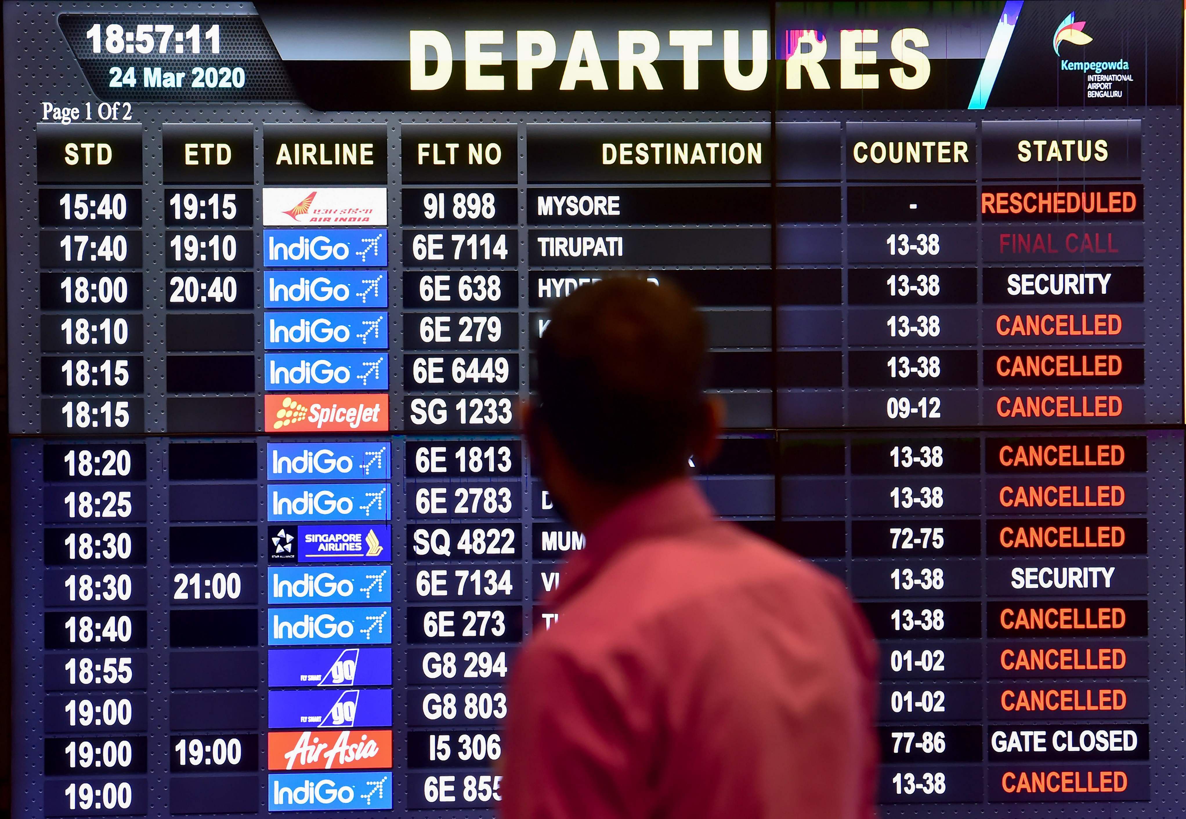 A passenger looks at the flight information board after several flights were cancelled in wake of coronavirus outbreak, at airport, in Bengaluru. (Credit: PTI)