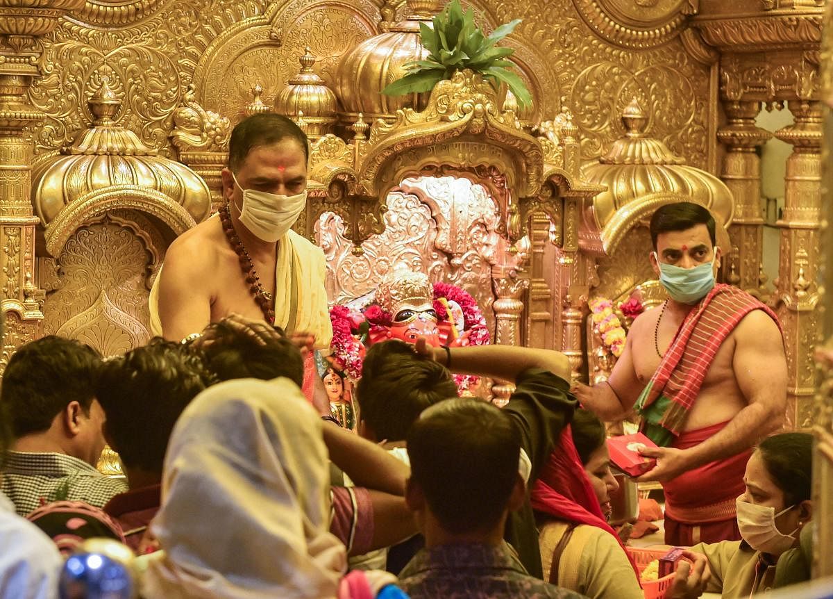 Priests wearing protective mask as a precautionary measure against the novel coronavirus (COVID-19), perform rituals at Siddhivinayak Temple in Mumbai, Friday, March 13, 2020. Credit: PTI Photo