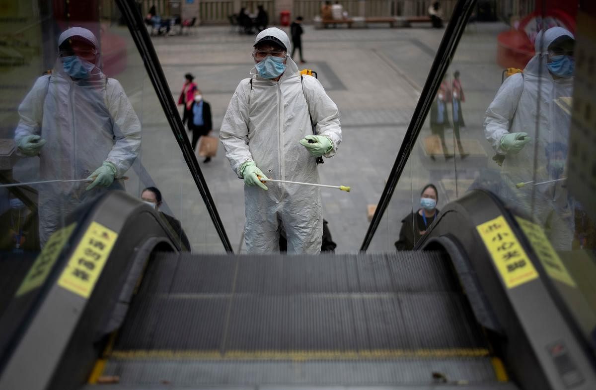 A worker wearing a hazmat suit disinfects an escalator in Hanjie shopping street in Wuhan, in China's central Hubei province on April 3, 2020. Credit: AFP Photo