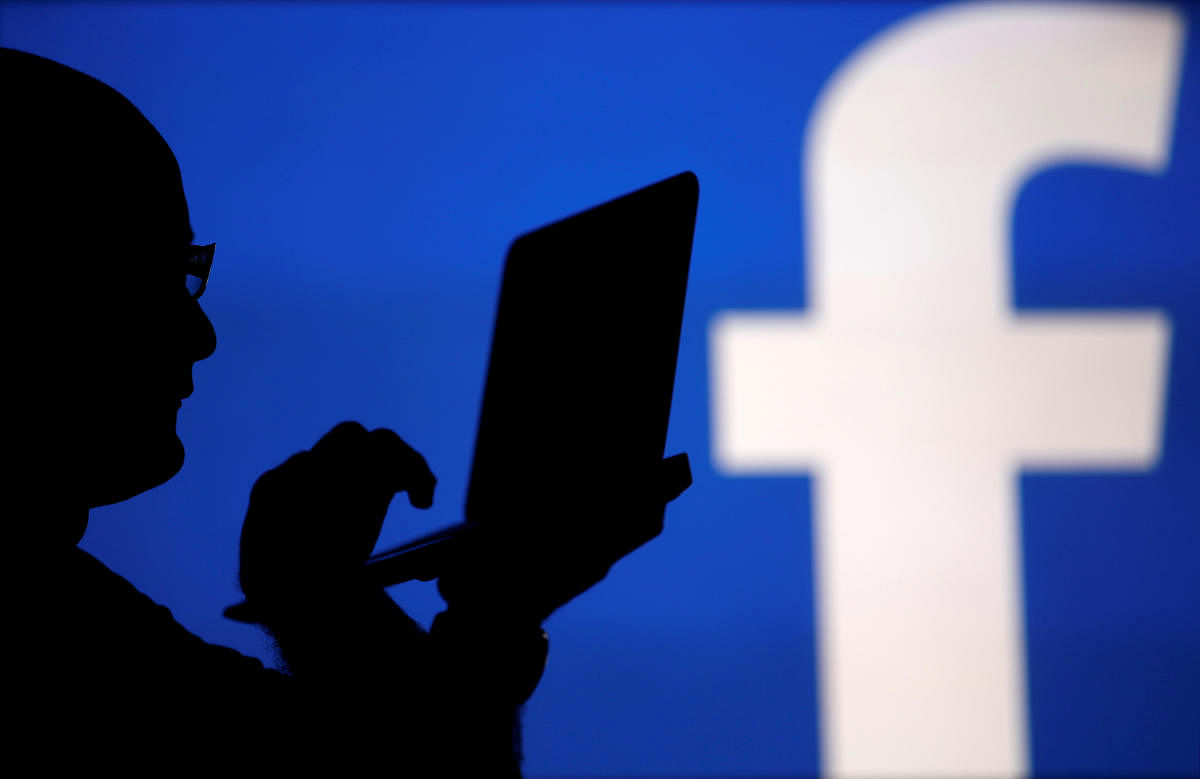 FILE PHOTO: A man is silhouetted against a video screen with an Facebook logo as he poses with a laptop in this photo illustration taken in the central Bosnian town of Zenica, August 14, 2013. REUTERS/Dado Ruvic/File Photo