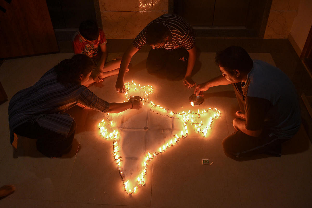 A family makes a map of India with traditional lamps in their flat in Surat. PTI