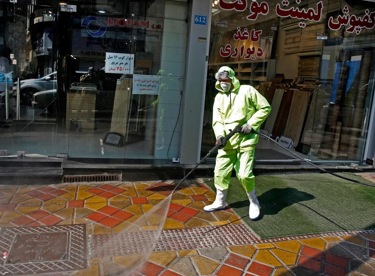 Iranian fire fighters and municipality workers disinfect a street. AFP file photo