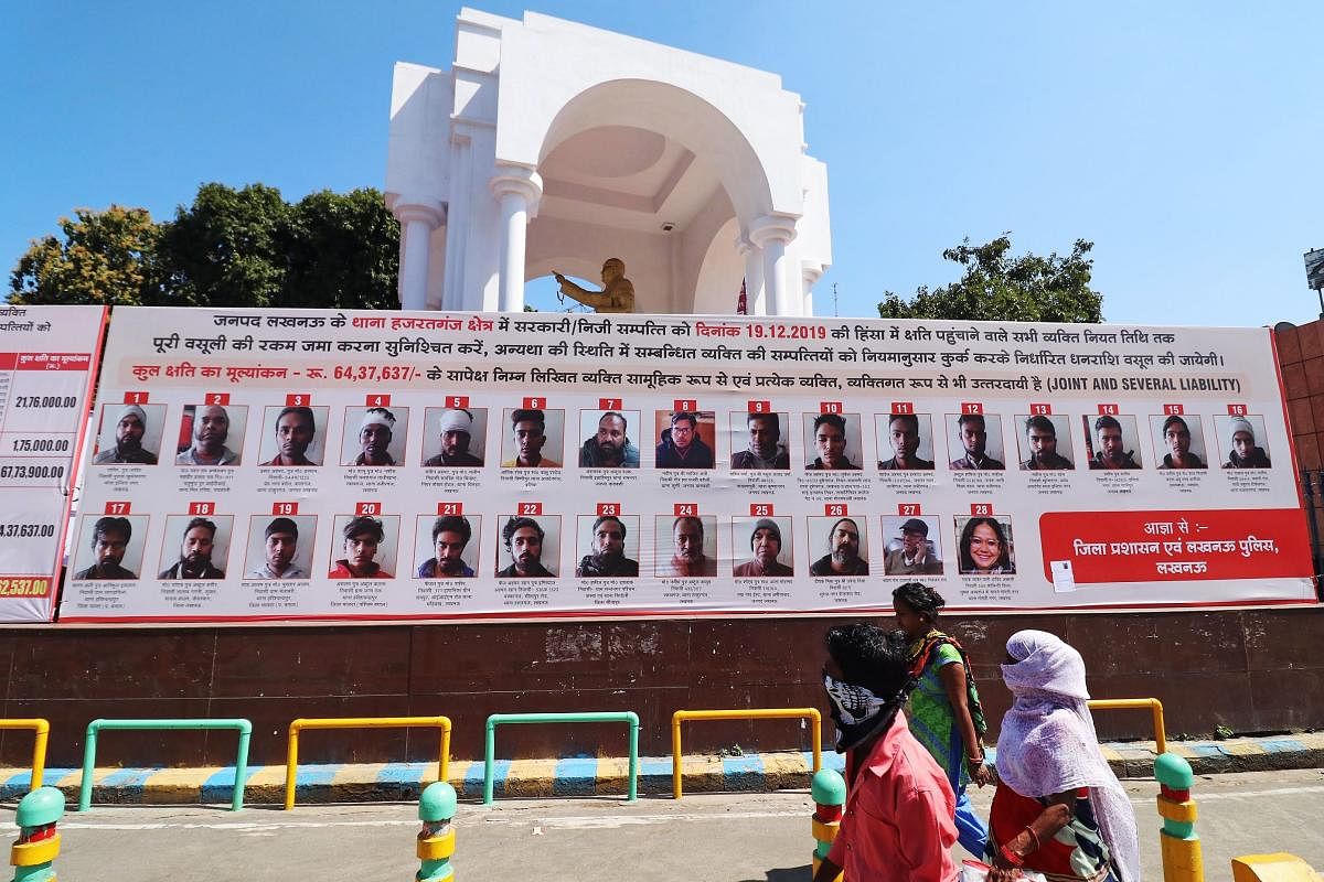 Commuters walk past a billboard installed by Uttar Pradesh authorities displaying pictures, names and addresses of people accused of vandalism during deadly protests in December against a contentious citizenship law, in Lucknow on March 9, 2020. Credit: AFP Photo