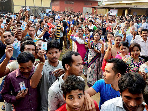 Voters wait in queues to cast their votes during the 2nd phase of Assam Assembly elections at a polling station at Bonda in Guwahati on Monday. PTI Photo